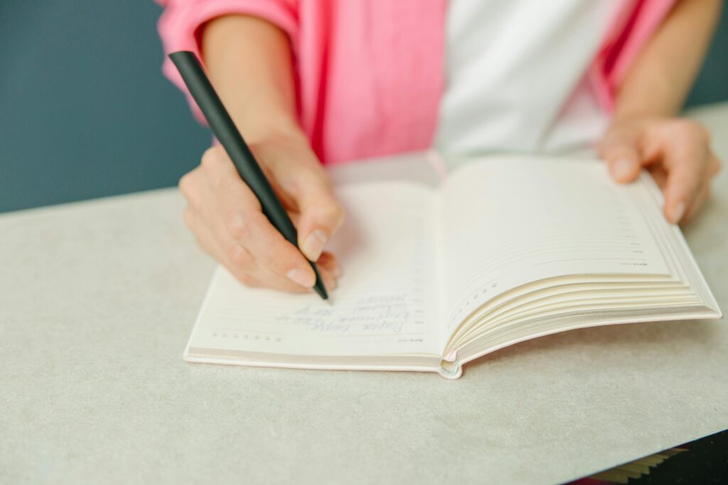 pexels-photo-8845108-8845108 Close-up of a person writing notes in a planner on a desk. Ideal for productivity themes.